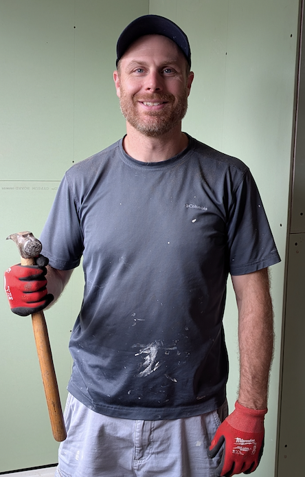 Ross holding a hammer on a renovation job site